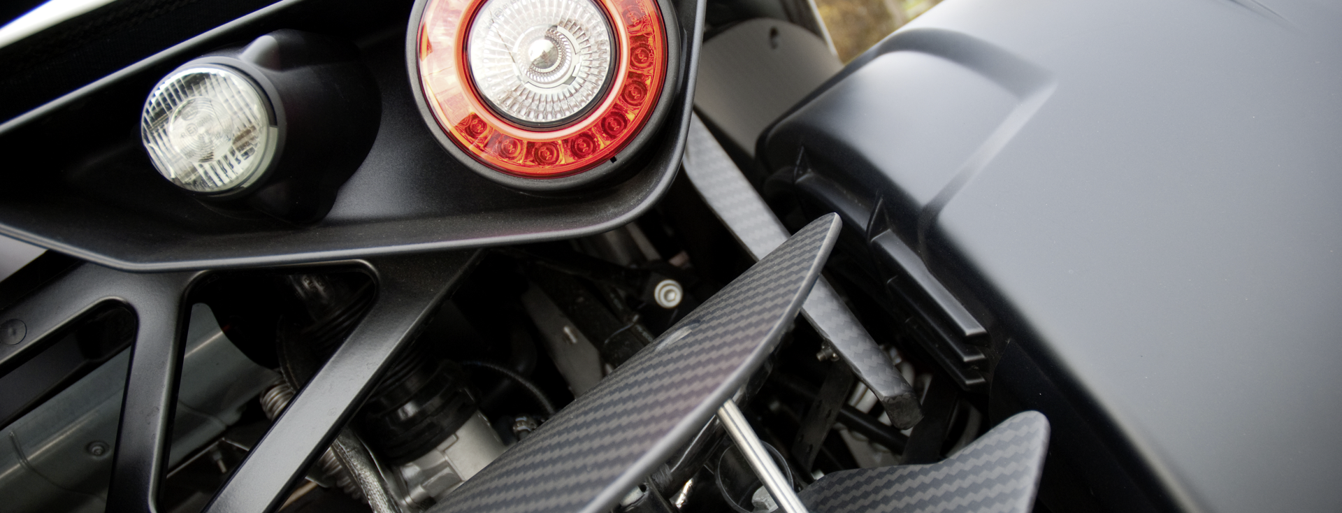 Close-up of a modern vehicle taillight with visible carbon components and technical structures in the rear section