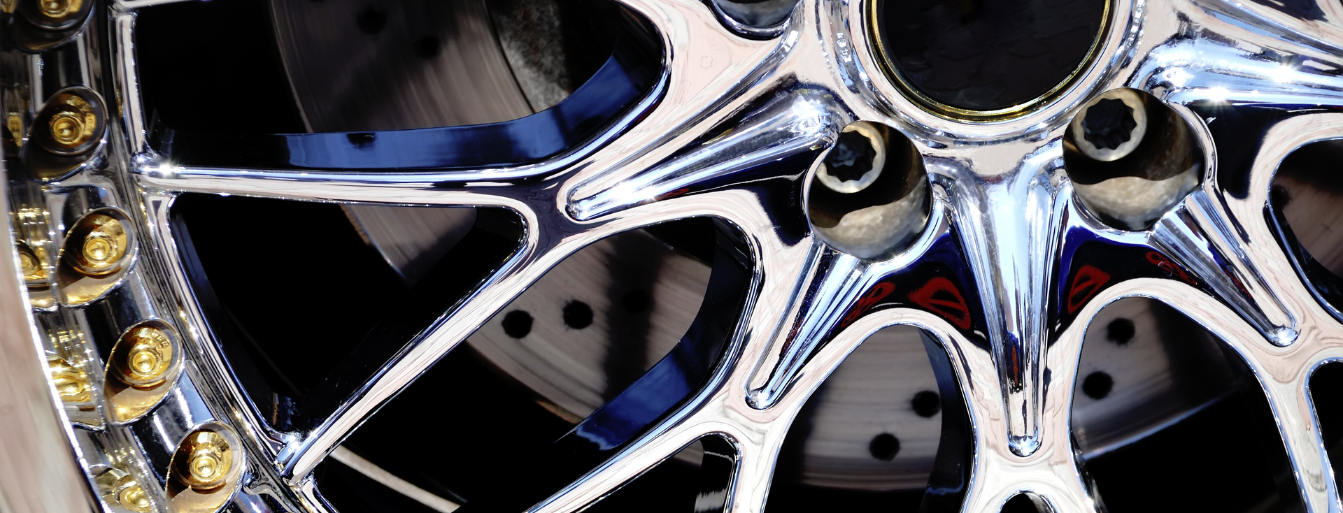 chrome-plated car wheel rim with gold bolts