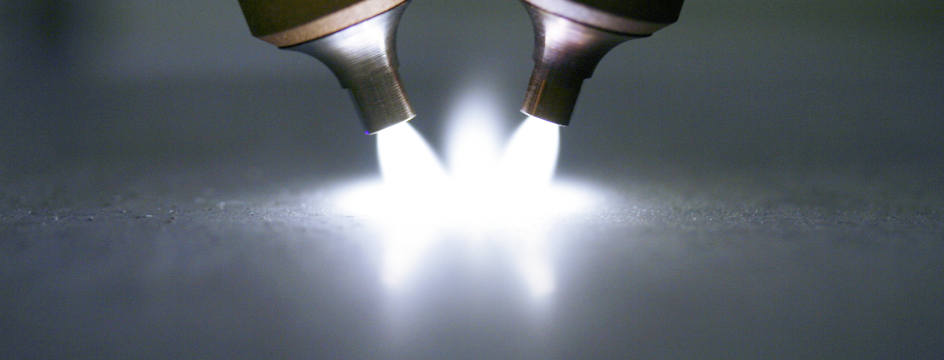 two plasma torches generate a bright, radiant arc on a surface. two plasma torches generate a bright, radiant arc on a surface.