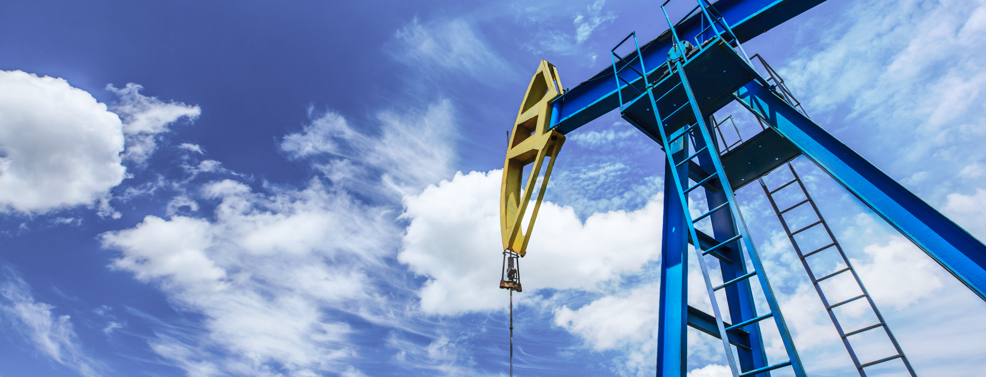 close-up of a blue and yellow oil pump against a blue sky close-up of a blue and yellow oil pump against a blue sky