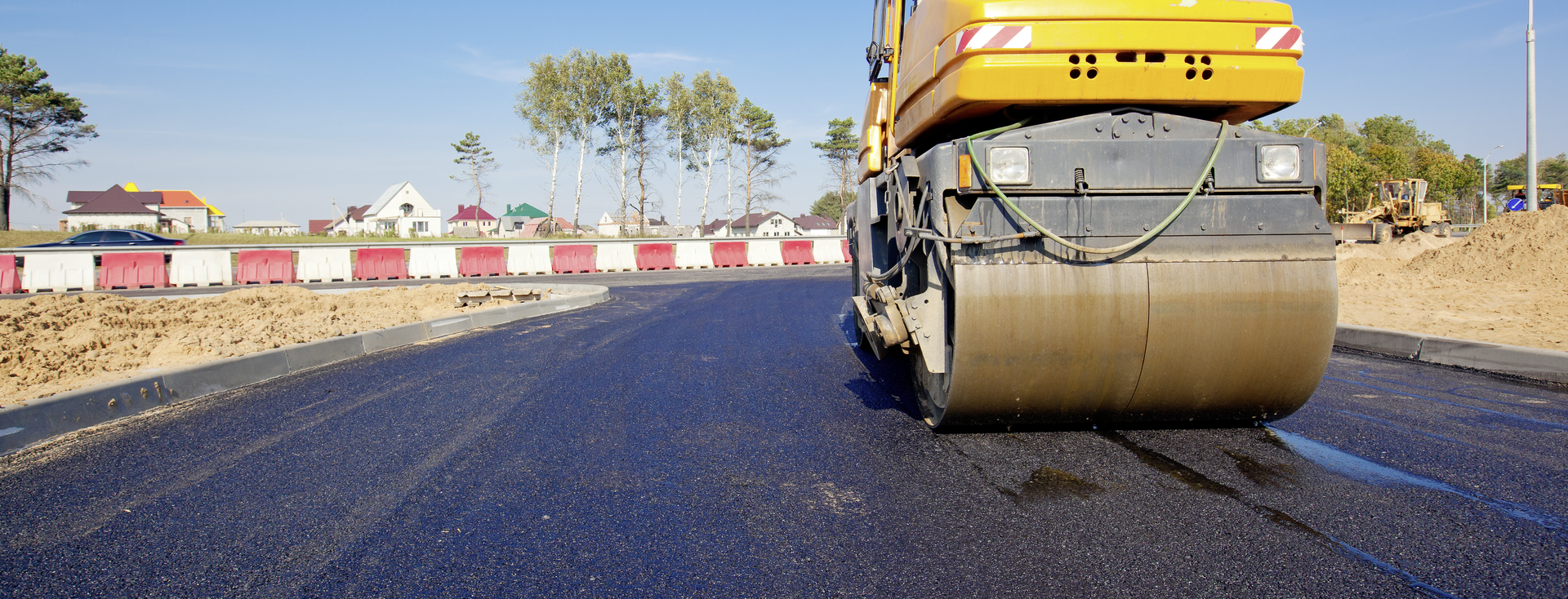 yellow roller compacts fresh black asphalt on a new road yellow roller compacts fresh black asphalt on a new road