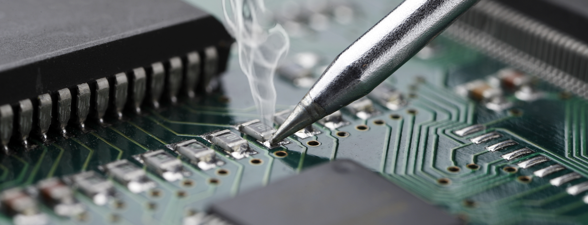 soldering iron soldering a small component onto a green circuit board soldering iron soldering a small component onto a green circuit board
