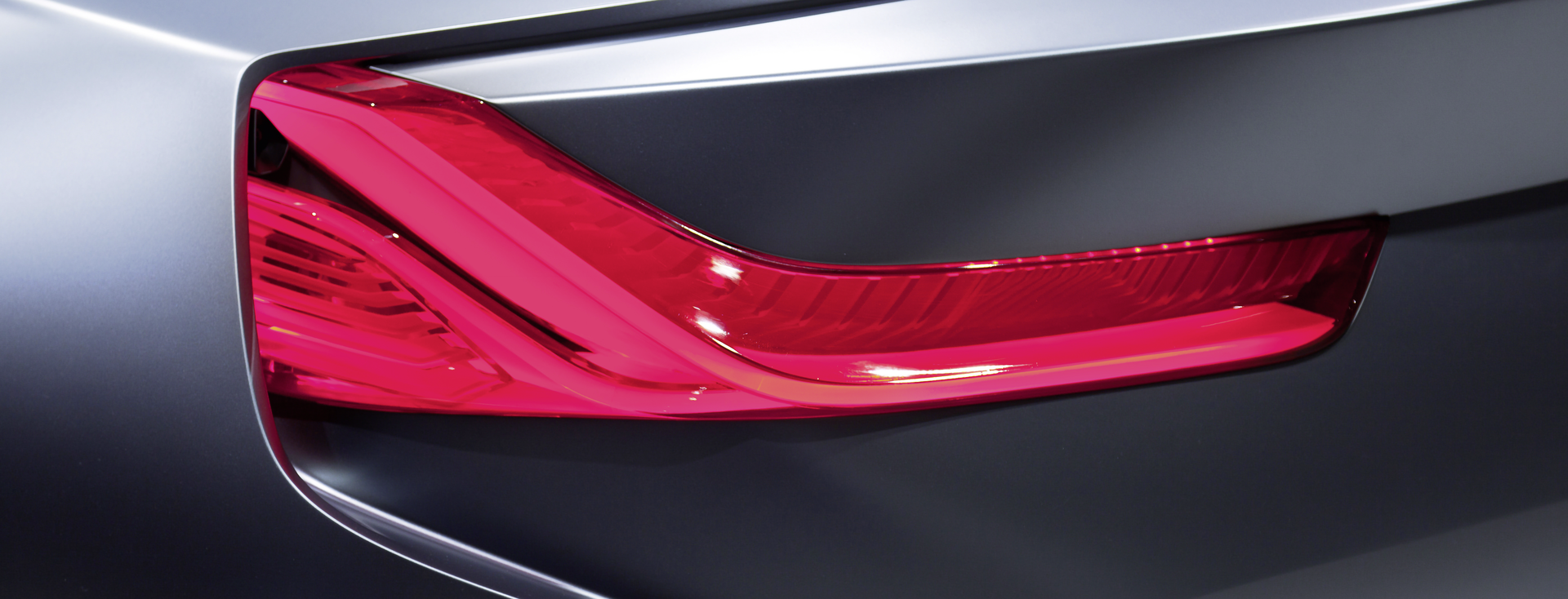 Nahaufnahme der roten Rückleuchte eines dunkelgrauen Autos Nahaufnahme der roten Rückleuchte eines dunkelgrauen Autos