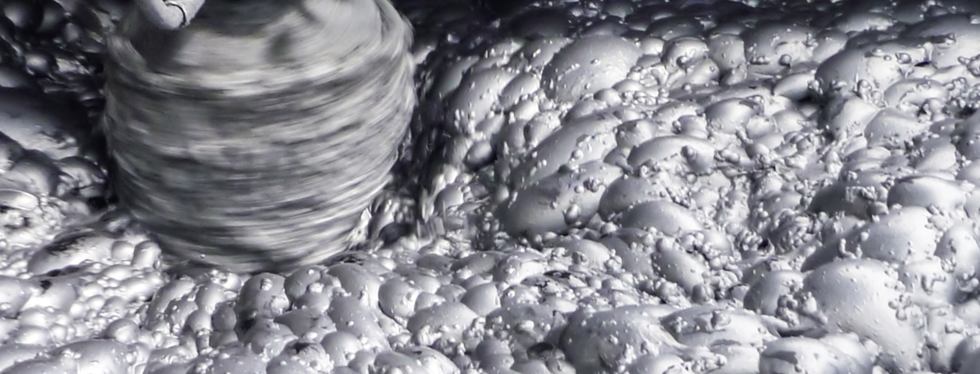 gray foam in a flotation tank is stirred up by an agitator