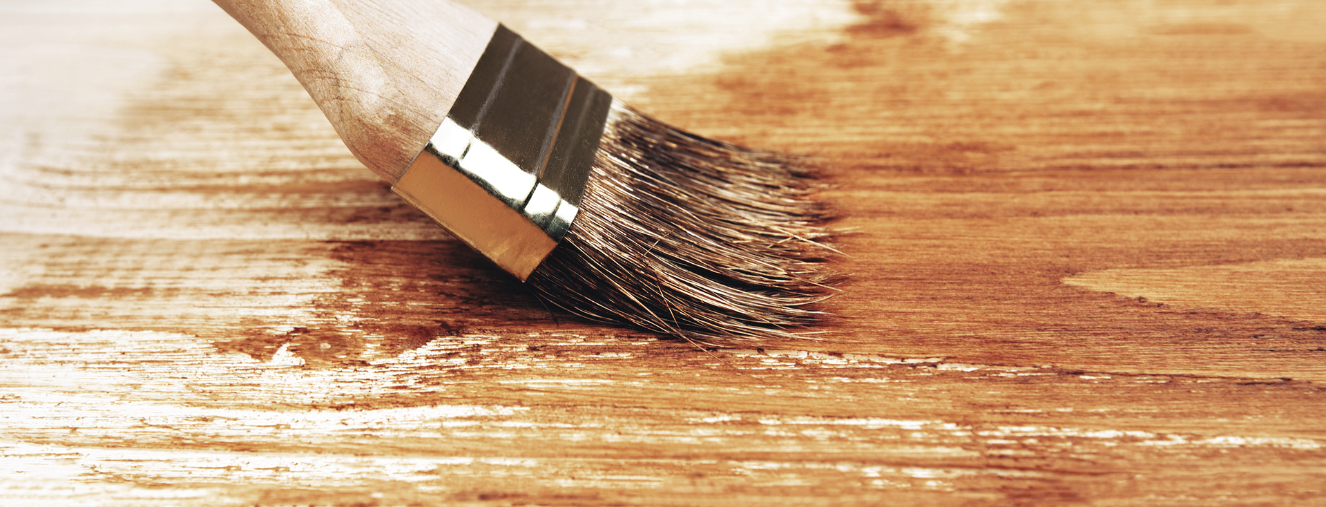 paint brush applies a protective varnish to a brown wooden surface paint brush applies a protective varnish to a brown wooden surface