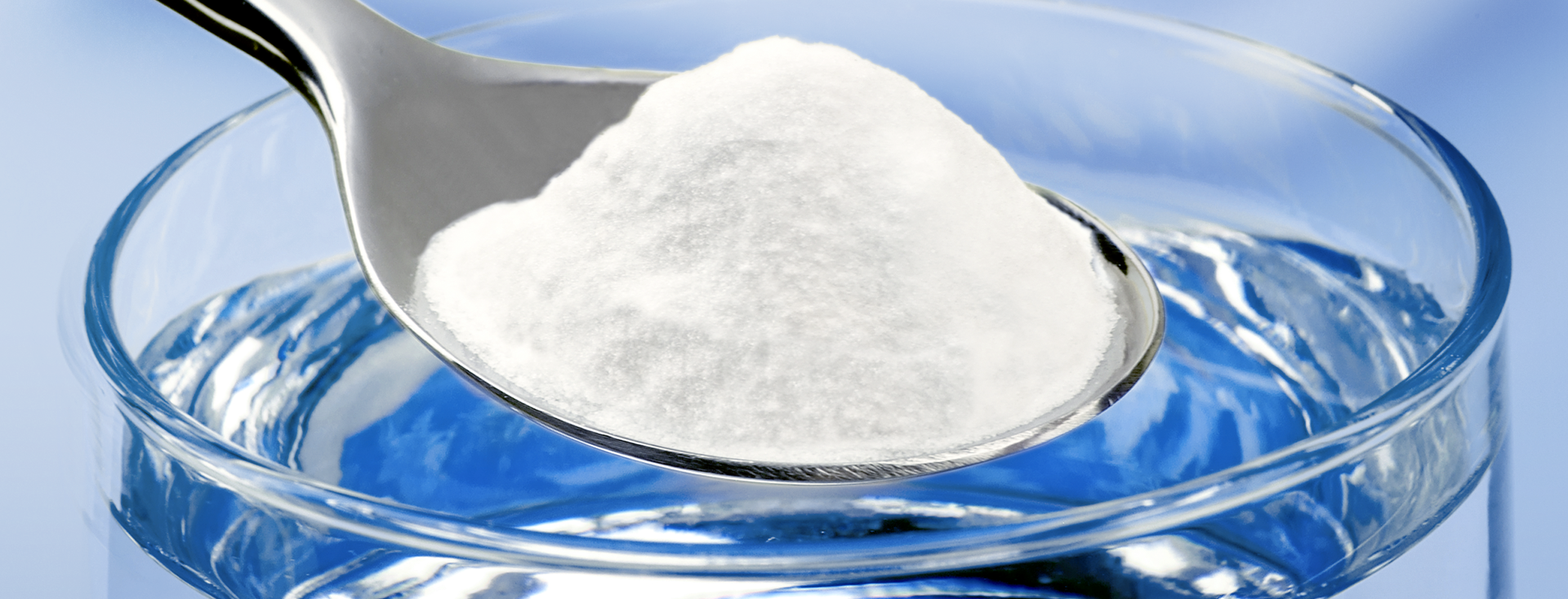 white powder on a spoon is added to a filled glass of water white powder on a spoon is added to a filled glass of water